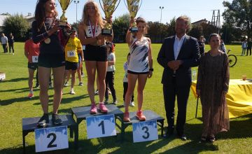 Sportowcy z pucharami stojący na podium.